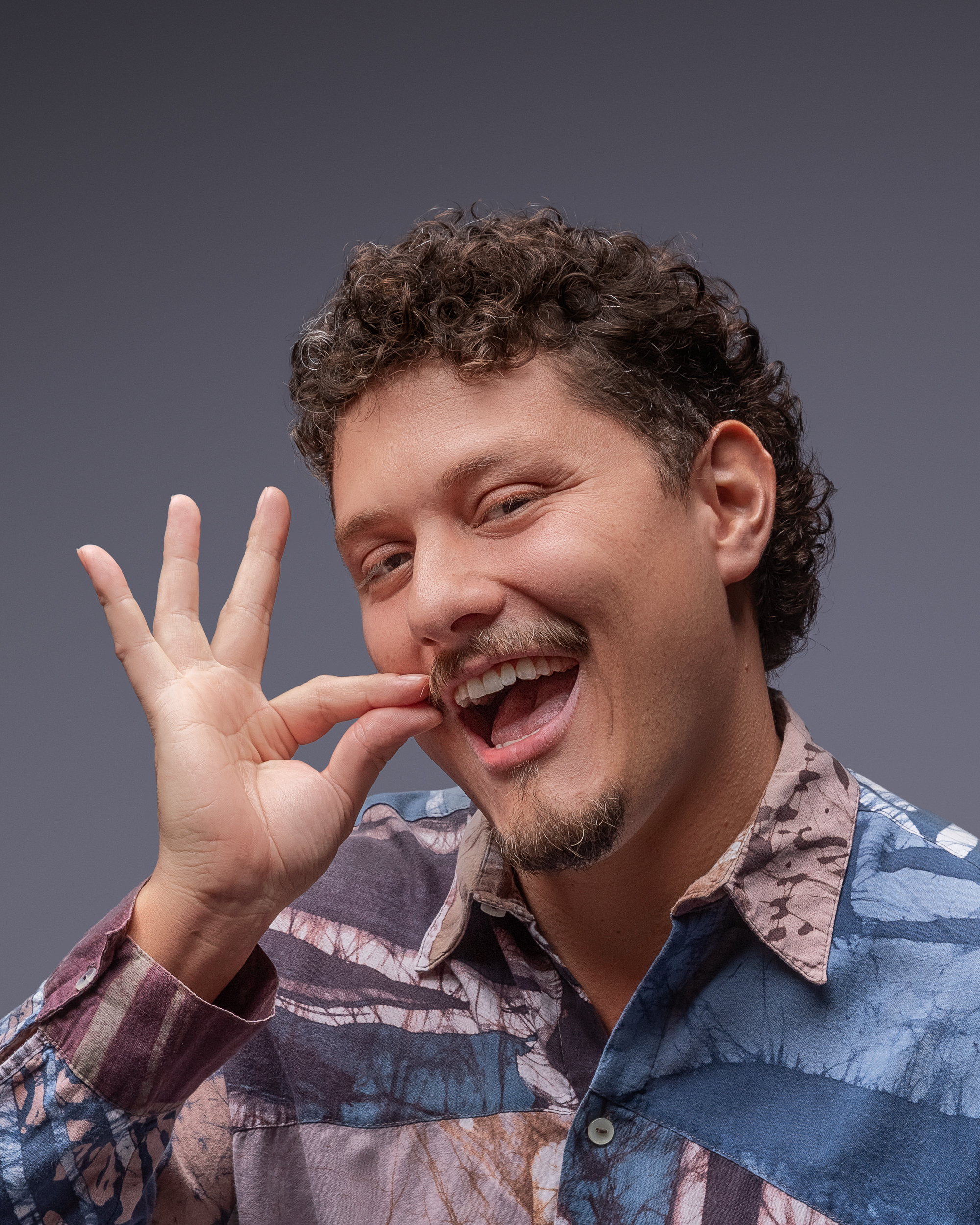 DJ Tilulu rindo, com a mão no bigode