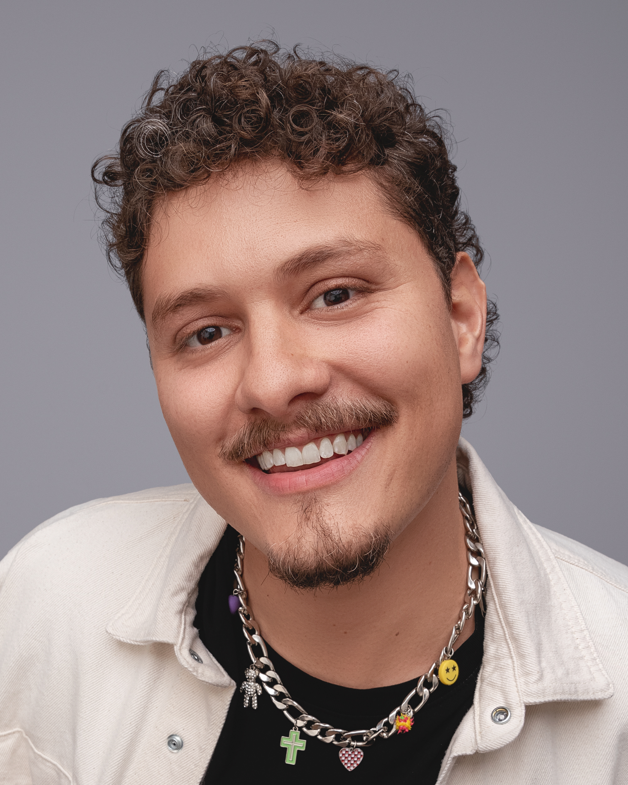 DJ Tilulu sorrindo com colar de pingentes coloridos