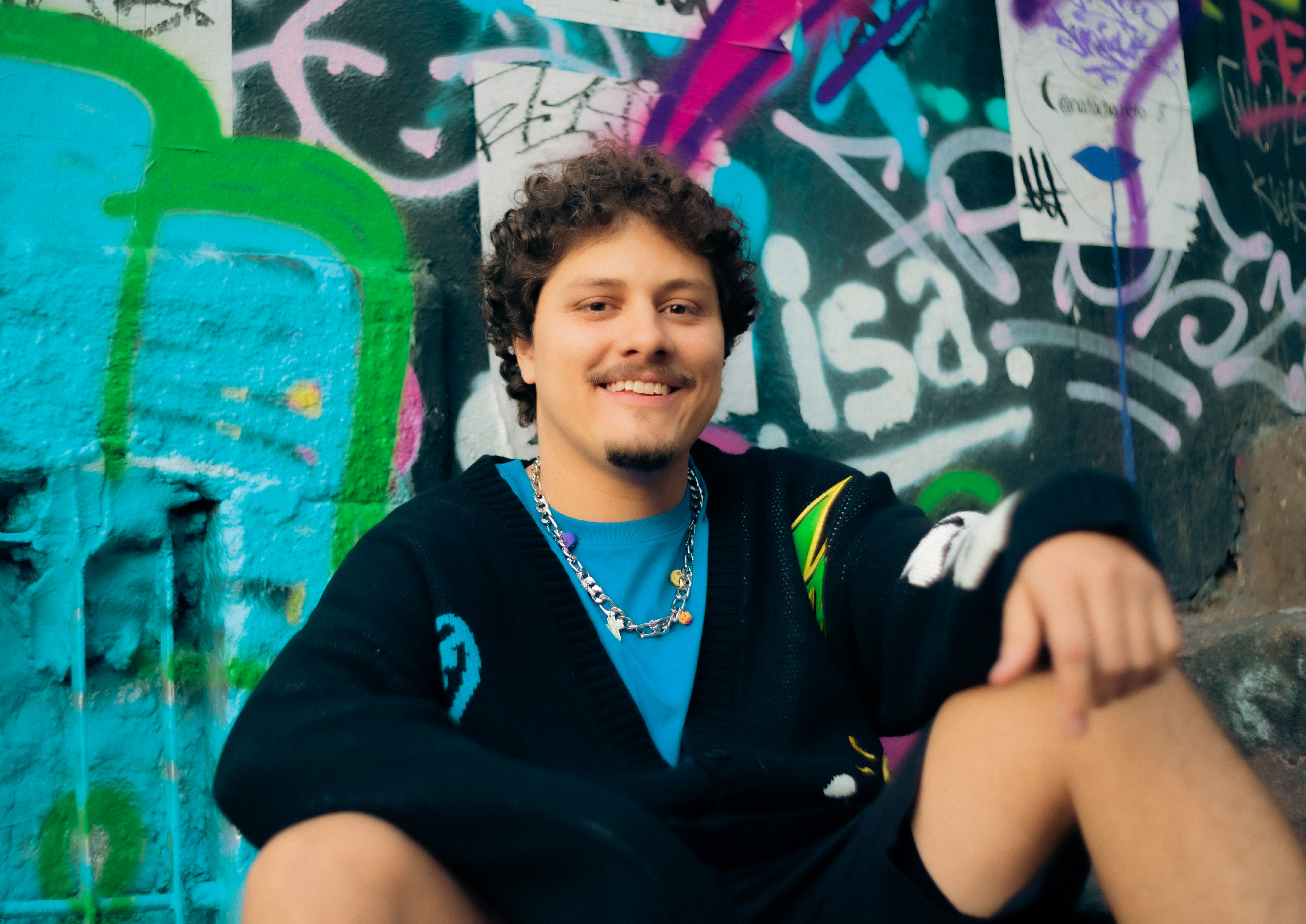 DJ Tilulu em frente a um muro grafitado