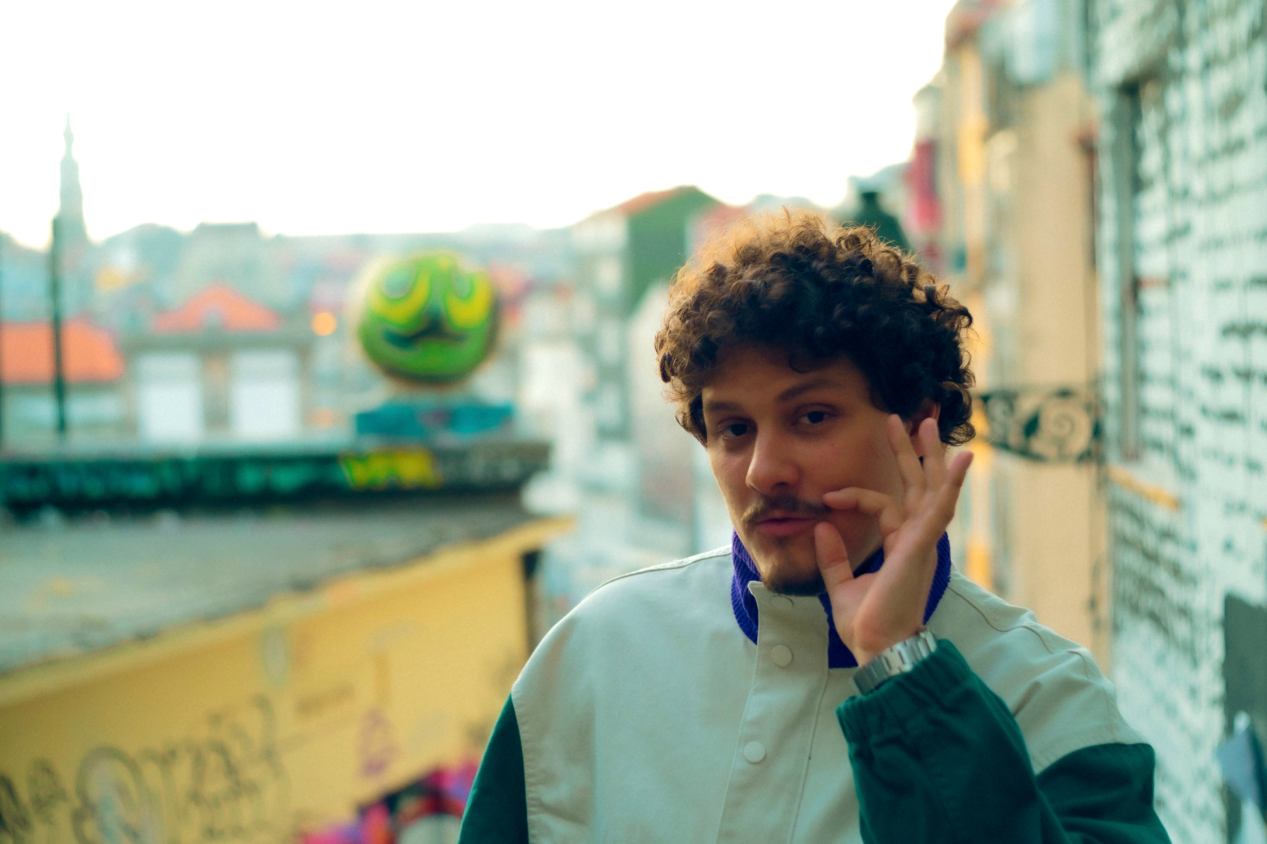 DJ Tilulu fazendo gesto com a mão perto do rosto, na rua