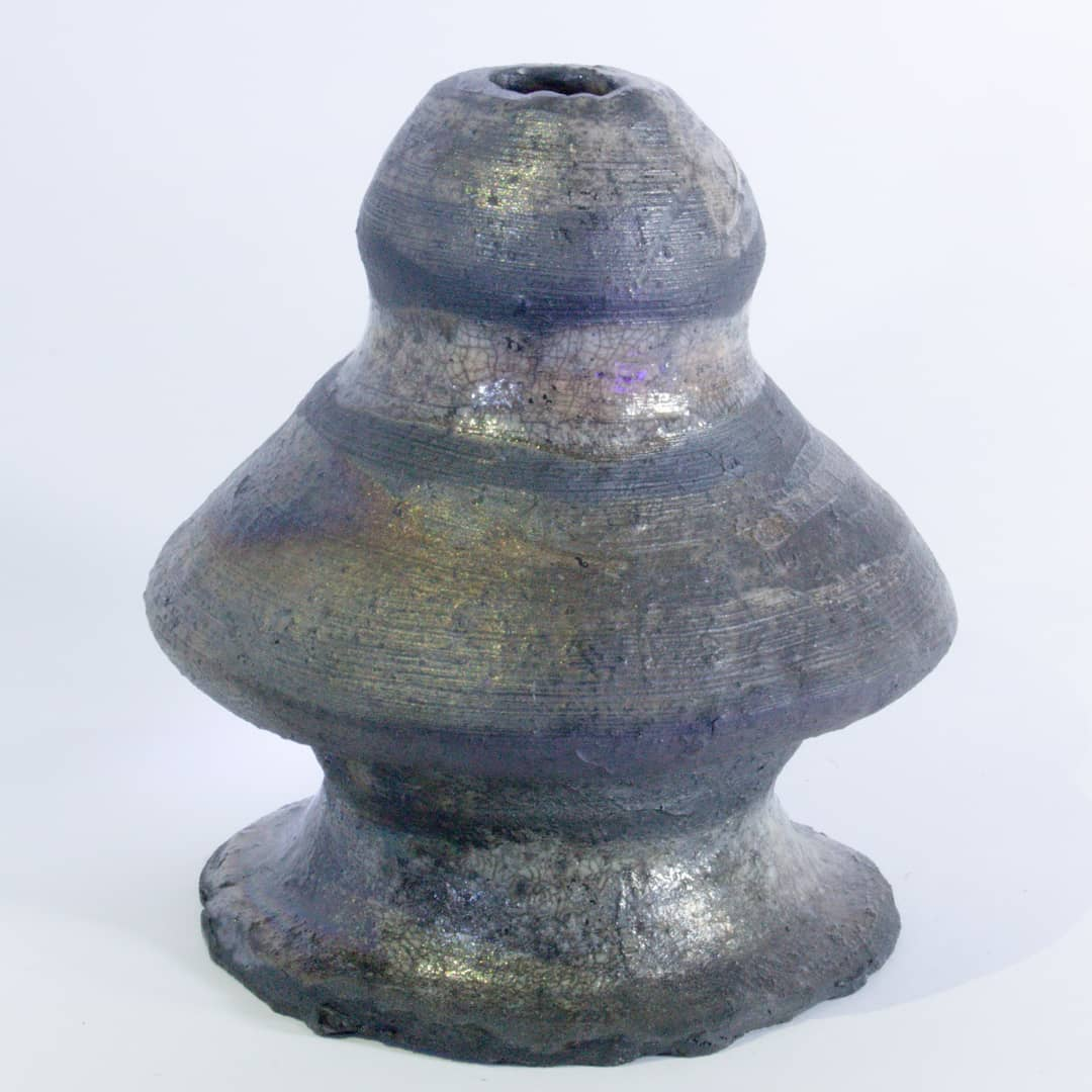 Peça escultórica em cerâmica de seções empilhadas e forma orgânica assimétrica, com esmalte escuro de brilho metálico e faixa craquelada iridescente